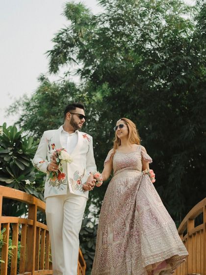 The couple takes a romantic walk across a wooden bridge during their Mehendi. This candid shot, with them holding hands and wearing sunglasses, is effortlessly cool and stylish.