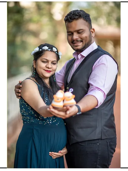 A happy portrait of the couple presenting the baby shoes to the camera.