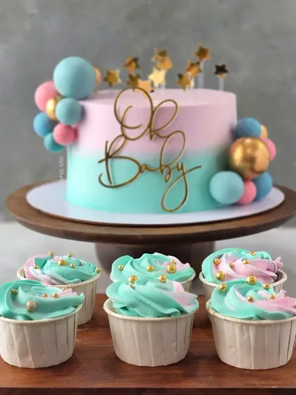 This "Oh Baby" shower cake is a perfect example of my custom, fondant-free work. The pastel pink and blue ombre effect is created with delicate whipped cream, complemented by matching cupcakes for a complete dessert table.