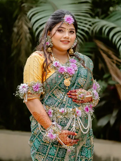 A beautiful portrait of the expectant mother cradling her belly, adorned with stunning floral jewellery for her baby shower.
