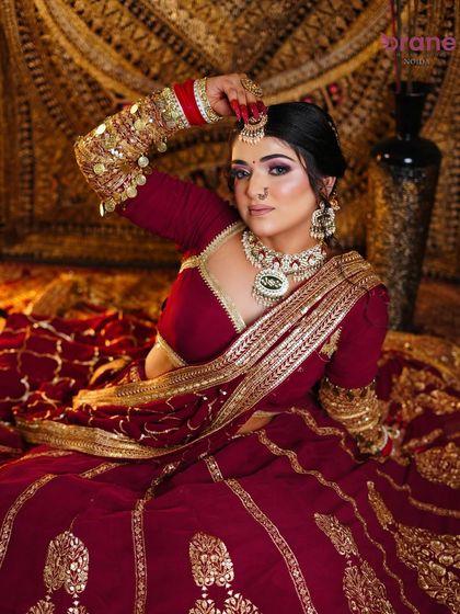 This pose showcases the full bridal attire, including the detailed arm jewelry and the elegant drape of the dupatta.