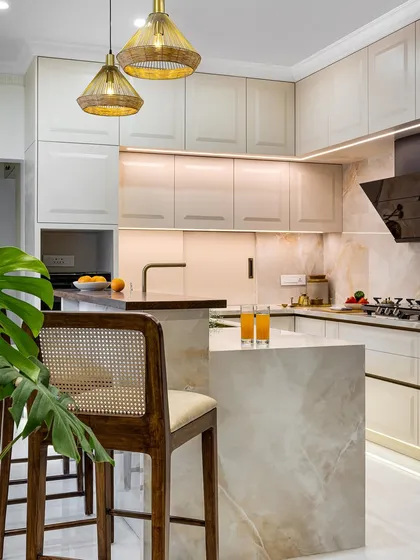 A kitchen should be both beautiful and highly functional. In this home, I designed a bright, open kitchen with a two-tiered breakfast counter and shaker-style cabinetry. The warm taupe and white palette, paired with finely veined marble, creates a clean, minimalist feel that is still warm and inviting.