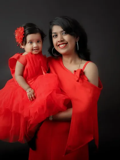 A mother and daughter duo in stunning matching red dresses. This elegant studio portrait against a dark background is both classic and striking.