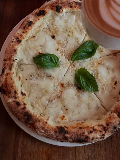 A top-down view of our Bianca pizza and a coffee. It's the perfect brunch or afternoon treat.