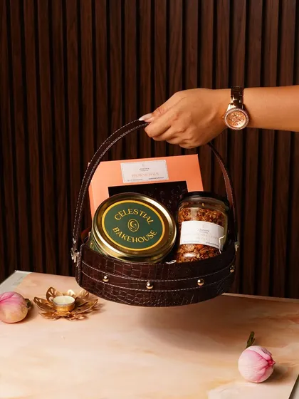 This is what a gift of love looks like. Our Raksha Bandhan gift basket, held here, is filled with our handmade eggless brownies, crunchy granola, and signature cookies, all packed into a beautiful, reusable leatherette basket.
