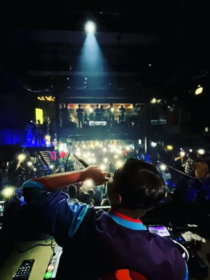 On the mic, connecting with the crowd as they light up the room with their phones.