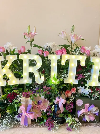 A stunning birthday arrangement for the actress Kriti Sanon, featuring her name in light-up letters nestled in a bed of gorgeous pink, purple, and white flowers.