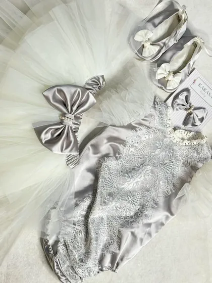 Welcoming the newest, tiniest clients with our newborn romper sets. This elegant silver satin romper features delicate lace detailing and comes with a matching bow and soft booties. It’s the perfect first outfit or a thoughtful gift for new parents.