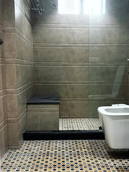 A view of the walk-in shower area, separated by a glass partition. The design includes a built-in tiled bench for convenience, and the consistent use of wall tiles creates a unified, spa-like feel.