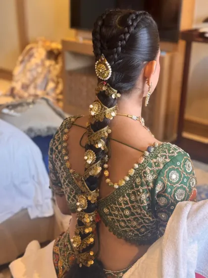 A detailed shot of a heavily accessorized bridal braid, featuring multiple layers of traditional gold ornaments. This style is ideal for a grand, royal wedding look.