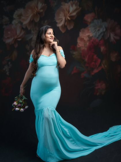 Elegance personified. In this breathtaking moment, our stunning mumma-to-be exudes serenity and grace in a soft, sea-blue mermaid gown with a long train.