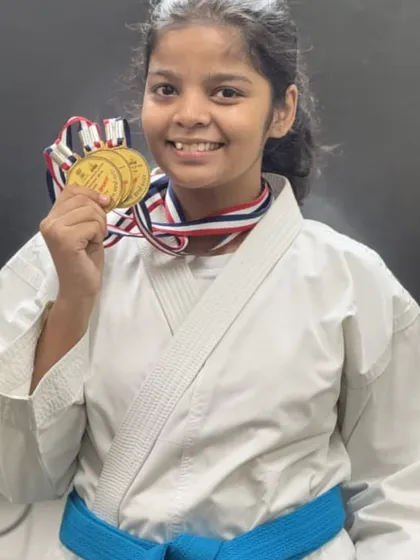 A proud smile from one of our young champions, showcasing her medals. Her success is a reflection of her commitment to consistent training.