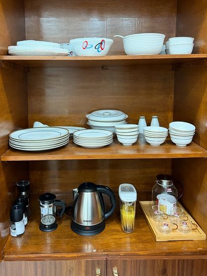 A simple wooden cabinet organized with everyday crockery and a beverage station. Even basic cabinets can be made highly functional with a bit of thoughtful organization.