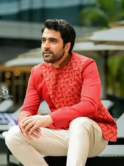 Abir Chatterjee in a stylish red ethnic jacket, seated by the pool. The composition is relaxed yet elegant, perfect for a modern menswear editorial.