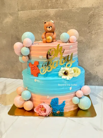 Celebrating a new arrival is so special. This "Oh Baby" shower cake is perfect for a gender reveal party, with its playful mix of pink and blue, a sweet teddy bear topper, and cute fondant details like a baby carriage and onesie.