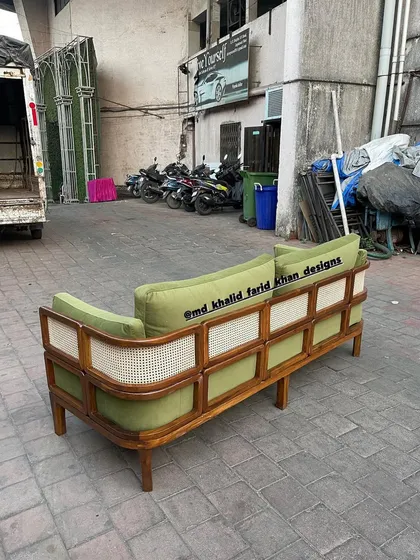 A custom green sofa with unique cane paneling on the back and sides.
