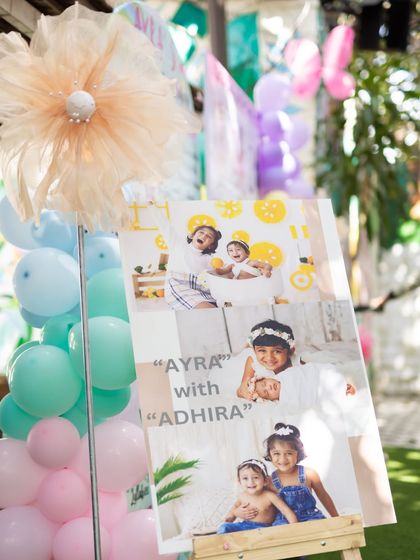 A personalized photo board welcoming guests to Ayra and Adhira's celebration.