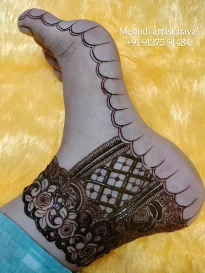 A close-up of the bridal foot design after the paste has been removed, showing the initial stain. The design includes a detailed ankle band with roses and a classic checkered filler.