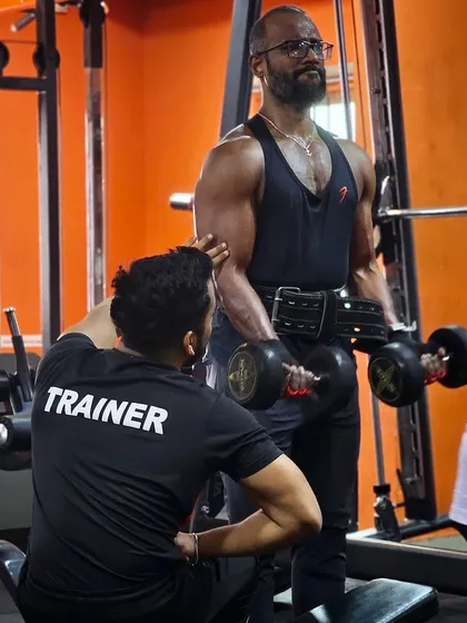 What does it take to be a champion? It takes desire and a coach who will push you there. Here I am providing hands-on assistance to a client during a dumbbell curl, ensuring every rep is performed with perfect form for maximum muscle engagement.