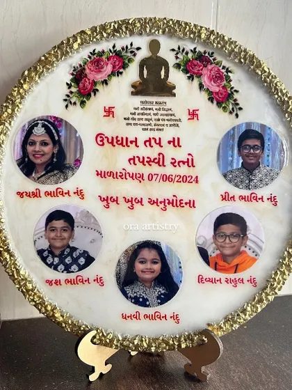 A large, circular frame created to commemorate a religious milestone for a family. It features multiple photos, names, and spiritual symbols.