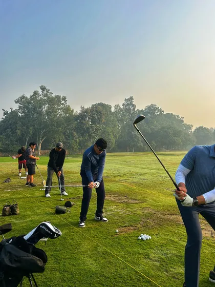 A group of golfers practices on the grass tees, their swings perfectly synchronized in this shot.