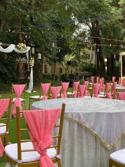 A view of the guest seating arrangement for a garden wedding. The chairs are neatly arranged with pink sashes, leading towards the main ceremony area, ensuring every guest has a great view.