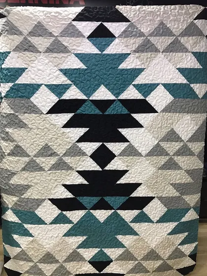 A modern quilt with a bold, tribal-inspired geometric pattern.