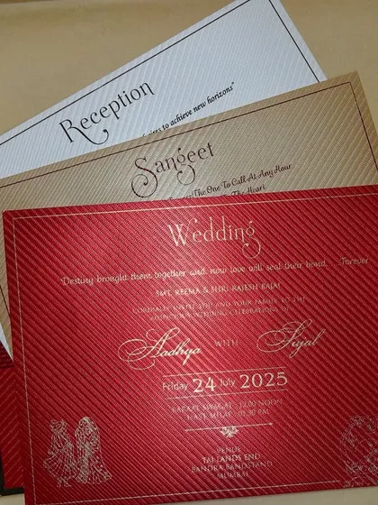 A fan of inserts in red, gold, and cream, showing the variety and richness of a complete wedding stationery suite.