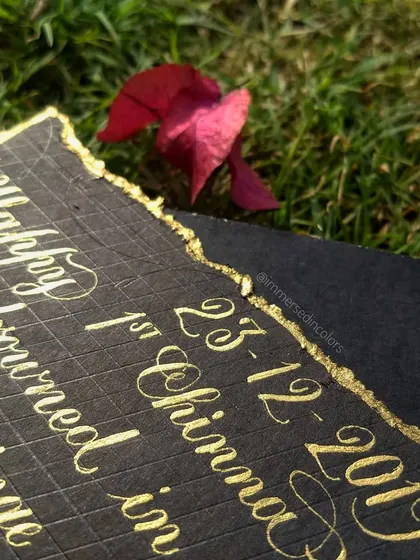 A detail shot of the handwritten letter, showing the texture of the paper and the torn gold foil edge. The combination of the elegant script and the rustic edge creates a beautiful contrast.