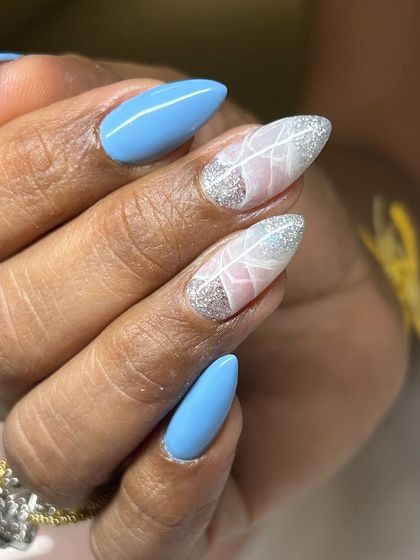 A beautiful and delicate nail art design. This set features a bright blue base with two accent nails showcasing a white feather design over a sparkling silver and pink background.