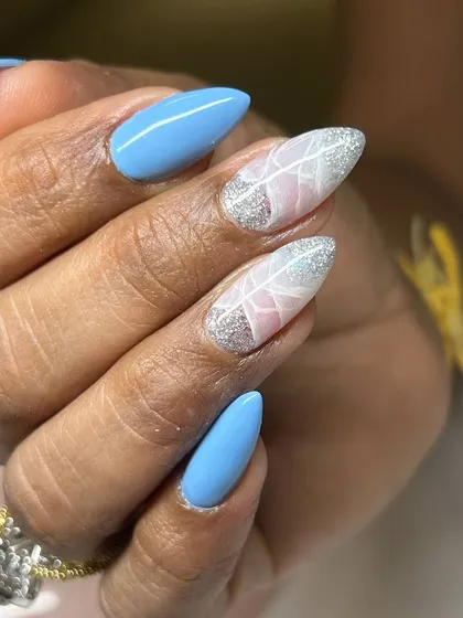 A beautiful and delicate nail art design. This set features a bright blue base with two accent nails showcasing a white feather design over a sparkling silver and pink background.
