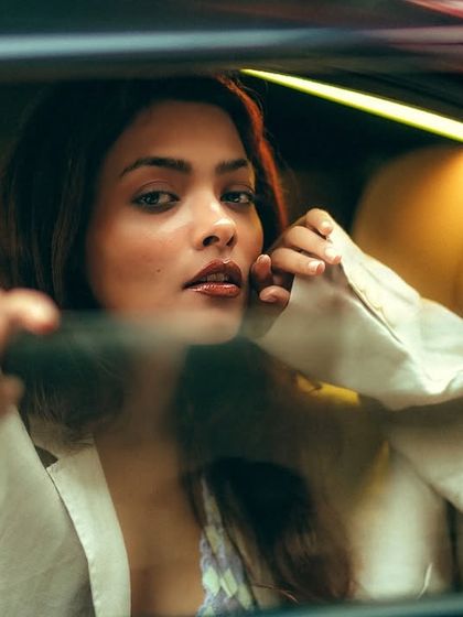 A beautiful and serene portrait through the glass. Her expression is calm and engaging, creating an intimate connection despite the physical barrier of the window.
