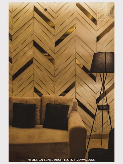 A close-up of a chevron-patterned wooden wall panel with inlaid mirror strips. This detail adds texture, warmth, and a touch of glamour to the living space.