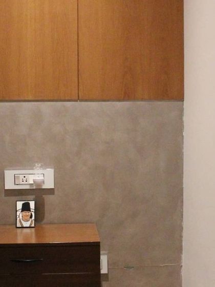 In this bedroom, we combined a micro-concrete finish on the lower wall with smooth wood paneling above. The custom bedside table continues the wood theme, creating a cohesive and textural design.