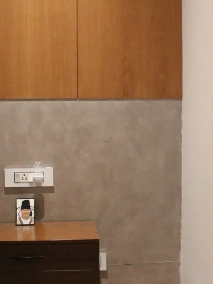 In this bedroom, we combined a micro-concrete finish on the lower wall with smooth wood paneling above. The custom bedside table continues the wood theme, creating a cohesive and textural design.