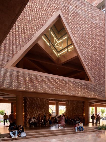 The ground floor of the university building is an open, columned space that serves as a social hub for students, sheltered by the massive structure above.
