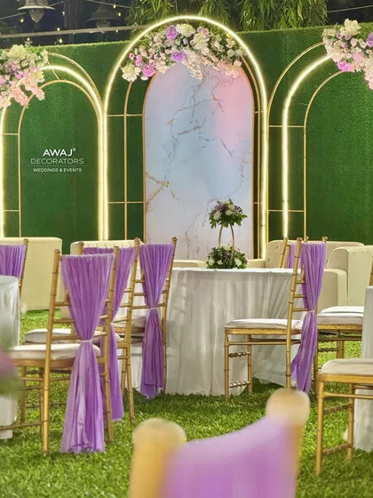 A dining table setup with purple chair drapes, complementing the lavender and white theme of the main stage.