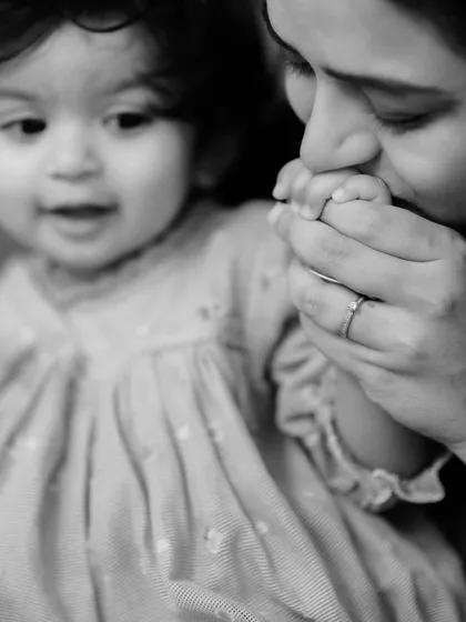 A tender black and white close-up of a mother gently kissing her baby's tiny hand. This intimate portrait focuses on the delicate details and powerful emotions that define the bond between a parent and child.