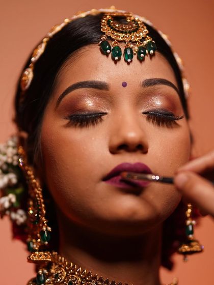 The artistry in progress. Here we are applying a bold lip color to complete this South Indian bridal look, featuring glamorous, shimmery eyes and a flawless base.
