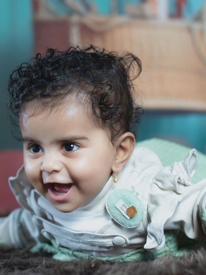 A close-up of a happy baby with curly hair, enjoying her time on the soft rug.