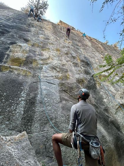 A low angle shot looking up at multiple climbers on a popular wall at Varlakonda. The energy of a busy crag day is contagious.
