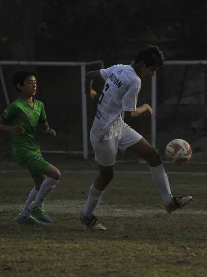 A player showing great ball control and technique to shield the ball from a defender in a league game.