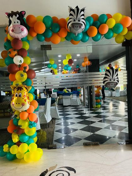 An entrance arch for a jungle-themed party, featuring colorful balloons and friendly animal faces to welcome the guests.