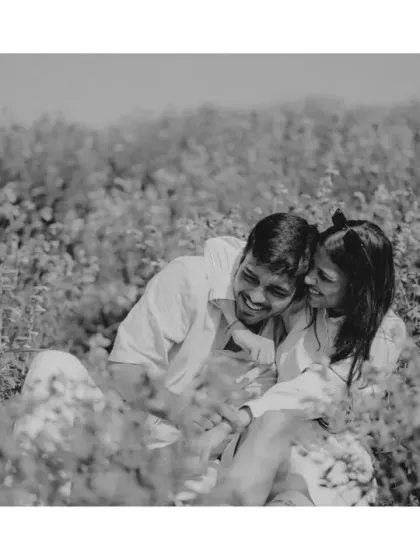 An intimate black and white shot of the couple sharing a laugh while sitting in the field. This image strips away color to focus purely on the emotion and joy of the moment.