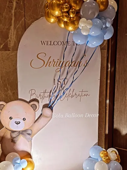 A sweet welcome sign for a first birthday celebration with a teddy bear theme, featuring a cute bear holding a bunch of balloons.