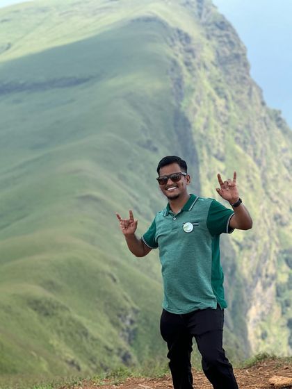 A happy trekker giving a rock-on sign, loving the vibe at Netravathi Peak.