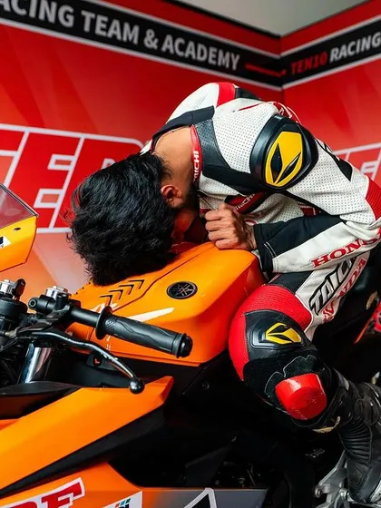 The moments before a race are about pure focus. Here, a rider connects with his machine in the pit garage, mentally preparing for the challenge ahead. This is part of the athletic discipline we instill.