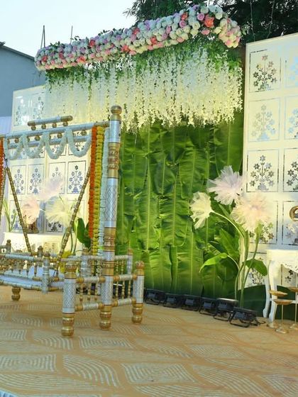 An angled view of the barsa ceremony stage, highlighting the layers of decoration. You can see the hanging floral arrangements, the textured backdrop, and the elegant side tables with elephant statues.