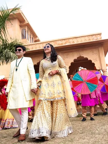 The couple walks hand-in-hand, leading the vibrant procession at their Mehendi carnival.