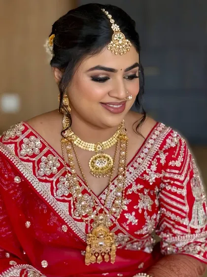 A smiling portrait of the bride in her traditional red attire. The makeup is designed to last through happy tears and hours of celebration.